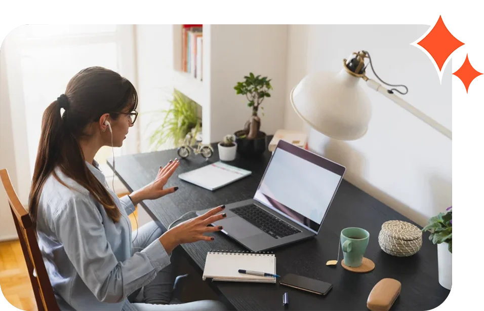 A woman sitting at her desk with two laptops.